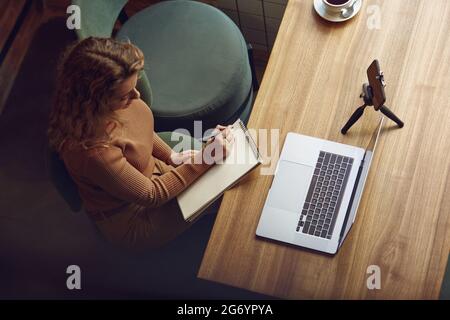 Female freelancer using laptop and smartphone for work Stock Photo