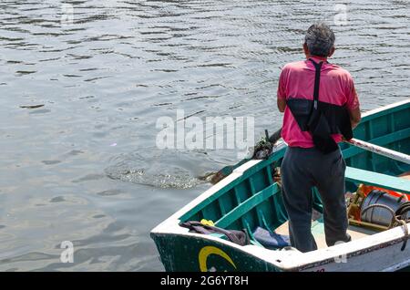 Fisherman from behind driving his boat on a sunny day. Stock Photo