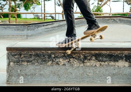 Skateboarder is doing a crooked grind trick on a bench in skatepark. Stock Photo