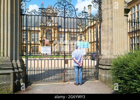 An elderly man stands at the locked gates of the Examinations Schools at the university of Oxford, England. Stock Photo