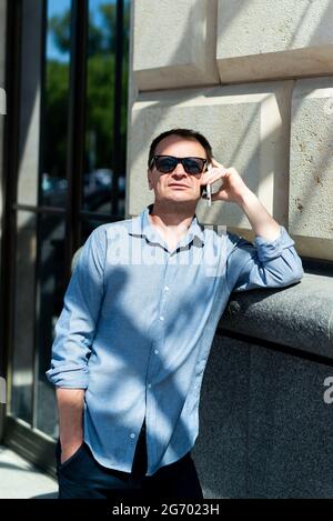Caucasian man forty years old businessman near the building talking on the phone. Stock Photo