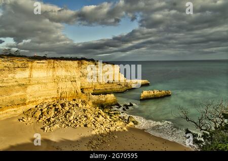 Limestone cliffs near Pontal, Algarve, Portugal light up in the evening sun during winter. Seagulls are resting on the small beach (Praia do Pontal) Stock Photo
