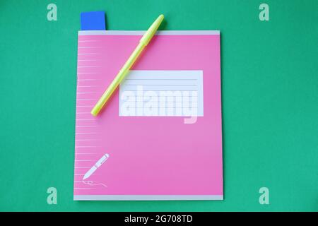 Pink notebook with stationery accessories on a green background. 1 September is the day of knowledge. Stock Photo