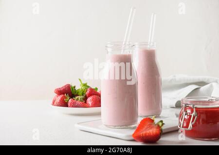 Healthy Ayurvedic Indian lassi or strawberry milkshake in bottles on white background. Drink to improve digestion. Stock Photo