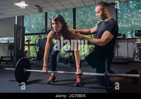 Personal Trainer Showing Young Woman How To Train Barbell Squats Exercise  In A Gym Stock Photo - Alamy