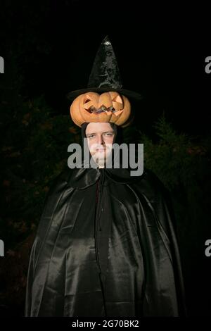 Portrait of a man with a pumpkin on his head. The guy in the Dracula costume. Stock Photo