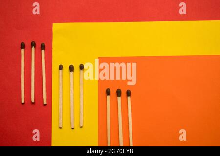 Some wooden matches on a clorful yellow, red and orange surface Stock Photo