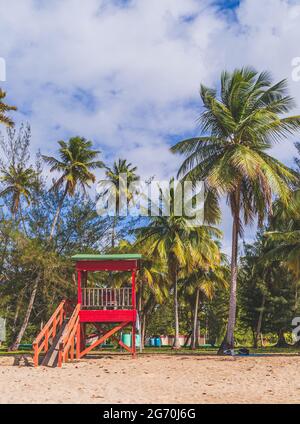 Red Life guard hut and palm trees on tropical beach. Luquillo Beach, Puerto Rico Stock Photo