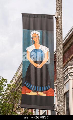 Holland, MI, USA - June 8, 2008: Closeup of street banner colorful painting showing Dutch woman in traditional garb against light blue sky. Parts of b Stock Photo