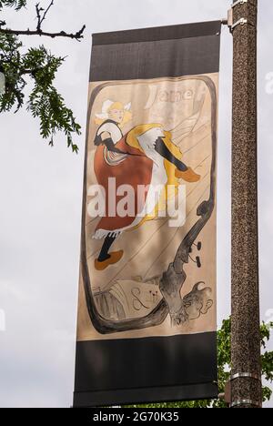 Holland, MI, USA - June 8, 2008: Closeup of street banner colorful painting showing dancing Dutch woman in traditional garb against gray sky. Stock Photo