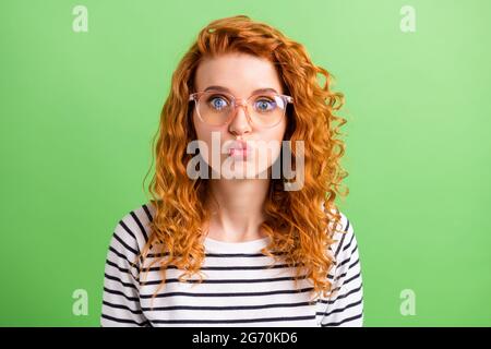 Photo of impressed sweet young woman wear striped shirt spectacles sending you kiss isolated green color background Stock Photo