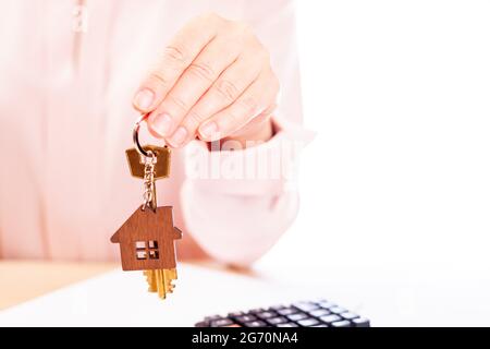A woman holds the key to the house, the real estate agent, the place under the text Stock Photo