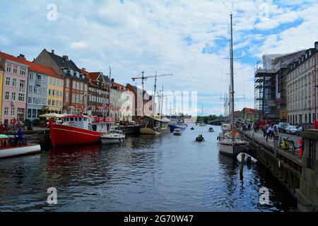 Copenhagen, Denmark- July 2021: Colorful old houses, cafes and restaurants, with boats docking along the canal of Nyhavn (New Harbour) on a gloomy day Stock Photo