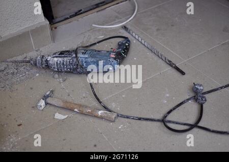 Hammer, chisel and electric drill lying on the tile floor. Renovation. Home improvement. Do It Yourself apartment repairing.  Stock Photo