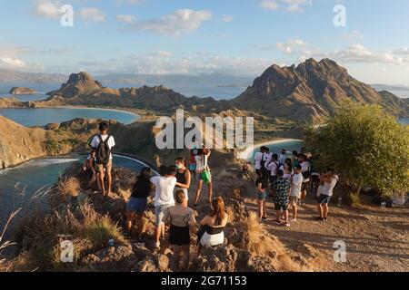 Padar, Indonesia - July 3 2021: A large group of Indonesian tourists pose for photo and takes selfies at the famous viewpoint of Padar island in the K Stock Photo