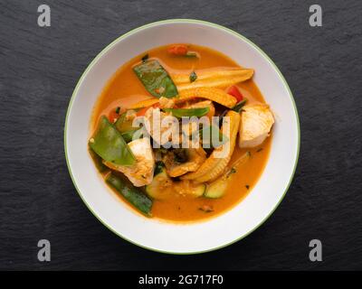 Spicy Red Thai Curry with Chicken and Vegetables in a Bowl, Top View Stock Photo