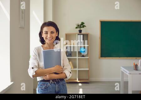 Confident smiling female teacher portrait holding digital tablet stand in class Stock Photo