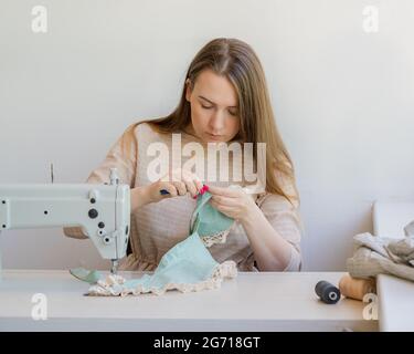 Young female tailor working on new garment at her workplace in studio Stock Photo
