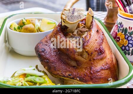 Traditional Czech roasted pork knuckle meat served with potatoes, herbes and vegetables Stock Photo