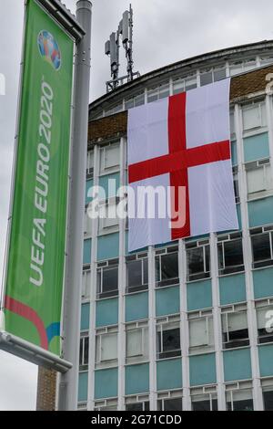 Wembley Park, UK. 10th July 2021.   Football's Coming Home,  Wembley Park is buzzing with excitement ahead of Sundays match and local businesses get behind the England team.     A giant England flag, the St Georges Cross, covers two floors of the College of North West London.   60,000 fans are set to descend to Wembley Park to watch England play Italy in the UEFA EURO 2020 Finals at Wembley Stadium on Sunday 11th July.  Amanda Rose/Alamy Live News Stock Photo