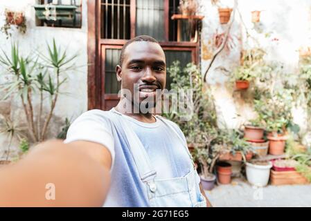 african attractive man raising his arm with his telephone to take a selfie. He smiles to camera. Stock Photo