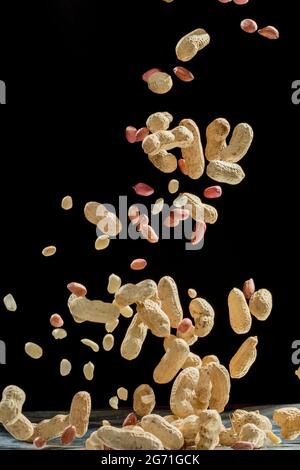 Realistic freeze motion of flying peanuts on black background. Stock Photo