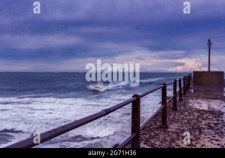 Fishing motor boat coming into shore at Port Alfred on a cold stormy late afternoon Stock Photo