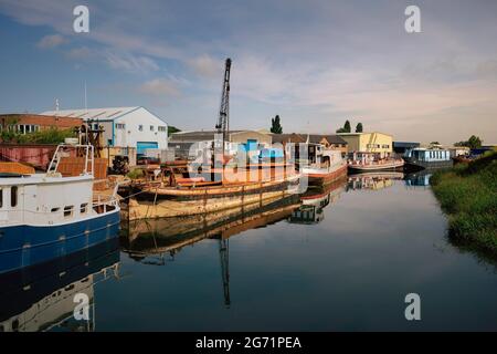 Derelict barges moored on the river Hull at various stages of restoration and refurbishment on a bright summer morning in Beverley, Yorkshire, UK. Stock Photo