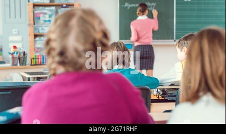 Teacher in class with fourth grade students in front of black board, education is so important I have been told Stock Photo