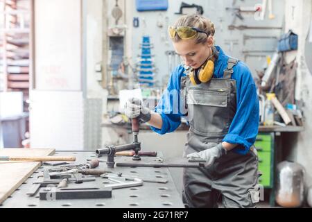 Female mechanic working with clamp and spanner on metal workpiece Stock Photo