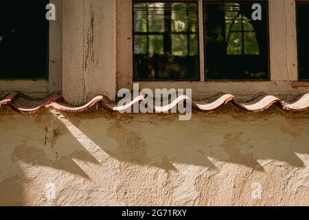 An old window in an old building of the last century. shadows from windowsill on wall. orange yellow painted wall Stock Photo