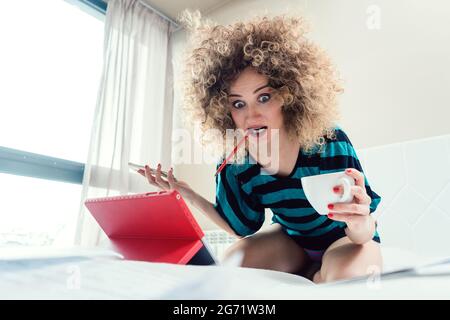 Woman student on her bed learning for exam in panic and despair Stock Photo