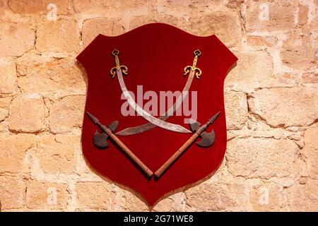 Swords and axes hung on the wall on a red velvet shield Stock Photo