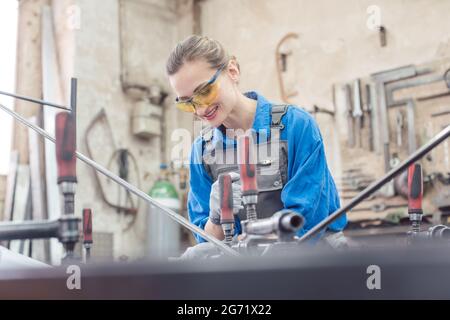 woman in Metal workshop with tools and workpiece working hard Stock Photo
