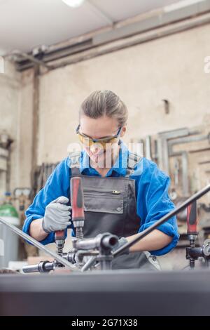 woman in Metal workshop with tools and workpiece working hard Stock Photo