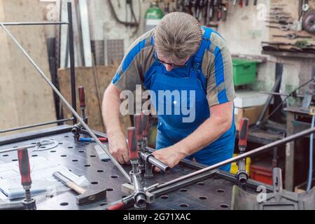 Worker in Metal workshop with tools and workpiece concentrating on his job Stock Photo
