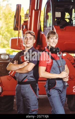 Two machinists for farm machinery in their garage standing shoulder to shoulder Stock Photo