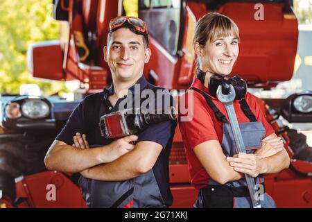 Two machinists for farm machinery in their garage standing shoulder to shoulder Stock Photo