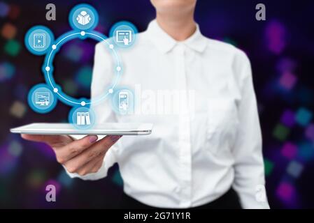 Lady In Uniform Standing Holding Tablet In Hand Presenting Virtual Modern Technology. Business Woman Carrying Tab Pointing For New Futuristic Tech. Stock Photo
