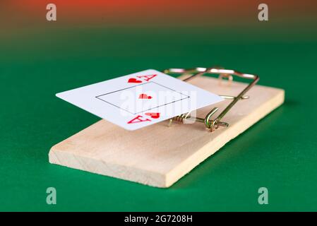 Playing card and mousetrap, game trap, on a green background, get into gambling addiction. Stock Photo