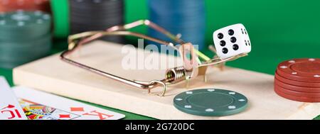 Dice and mousetrap, game trap, on a green background, get into gambling addiction. Stock Photo