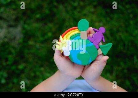 Child hands holding earth model with clay rainbow. ecology concept. top view Stock Photo