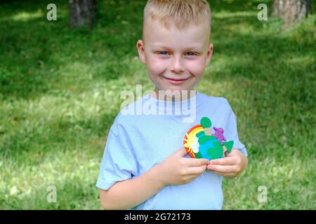Portrait of a cute boy holding an earth model with clay rainbow. ecology concept.outdoor Stock Photo