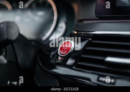 Sports car dashboard with focus on red engine start stop button. Button engine start and engine stop. Car inside. Ignition remote starter. Modern car Stock Photo