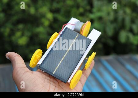 Unique solar powered car with 5 wheels and run by solar panel held in hand that shows creative hobby electronic projects concept Stock Photo
