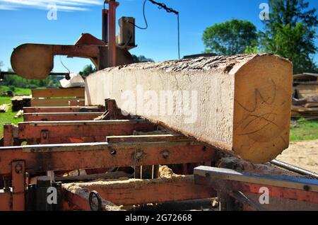 sawing logs on a mobile sawmill. log on the sawmill. preparation for cutting wood Stock Photo