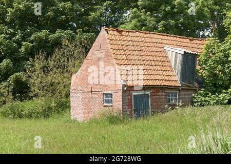 Old decaying shed with red bricks and orange tiles near Ferwert in The Netherlands. Stock Photo