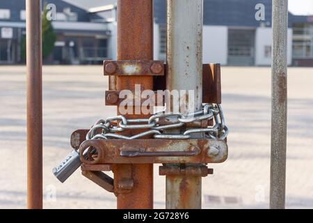 Locked rusty metal fence with chain and padlock combination lock. Closed borders immigration or lockdown concept. Image with selective focus. Stock Photo