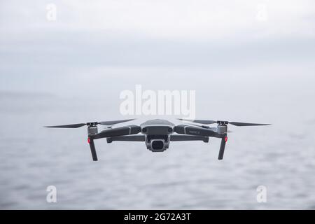 CORNWALL, UK - JUNE 29, 2021.  A DJI Mavic Pro 2 unmanned drone flying above water and facing the camera with copy space Stock Photo