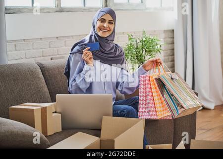 Happy Muslim woman holding a card and a bunch of gift bags Stock Photo